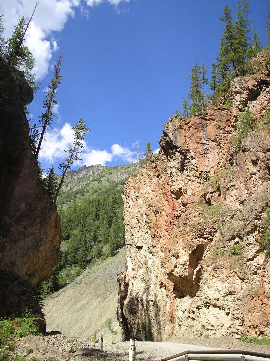 Один из самых известных природных памятников Республики Горный Алтай — Красные Ворота. Это величественные отвесные скалы высотой 50 метров, сложенные из пород насыщенного красного цвета. Горы словно бы расходятся в две стороны, освобождая путешественникам узкий каменистый проход. В этом обзоре мы расскажем о том, где находятся Красные Ворота в Горном Алтае, чем они известны и какие достопримечательности можно увидеть рядом с ними.

 
Где находятся Красные Ворота Горного Алтая

Памятник природы расположен в Улаганском районе республики Горный Алтай на стыке двух горных хребтов: Курайского и Айгулакского. Для путников, впервые проезжающих по маршруту, Красные Ворота открываются неожиданно. У подножия скал течет маленькая горная речка Чибитка. Под шум ее вод в узком проходе скал раздается звонкое эхо, которое кажется здесь особенно завораживающим.

ВАЖНО! Красные Ворота красивы в любое время года. Но если вы решите отправиться в путешествие в Горный Алтай зимой — будьте осторожны. Дороги здесь узкие, участок Улаганского тракта, на котором находятся Красные Ворота, не огорожен, возможны снежные заносы.
