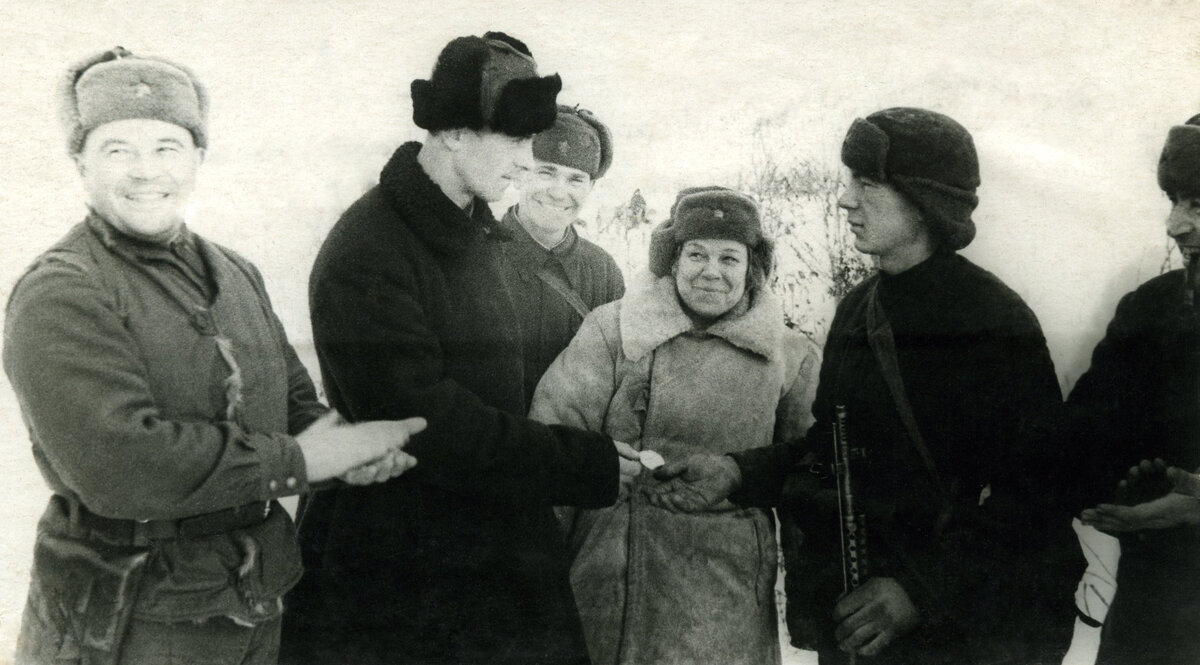 Машинист электровоза В.Г. Трофименко (2-й слева) вручает именные часы лучшему снайперу 3-й гвардейской стрелковой дивизии Т. Григорьеву на передовой линии фронта. Декабрь 1941 г. -  январь 1942 г.