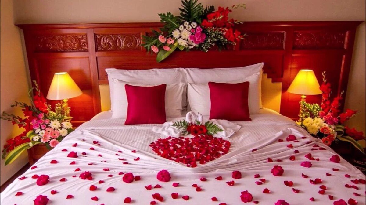 Спальня для молодоженов. Кровать для молодоженов. Лепестки роз на кровати. Романтическая обстановка.