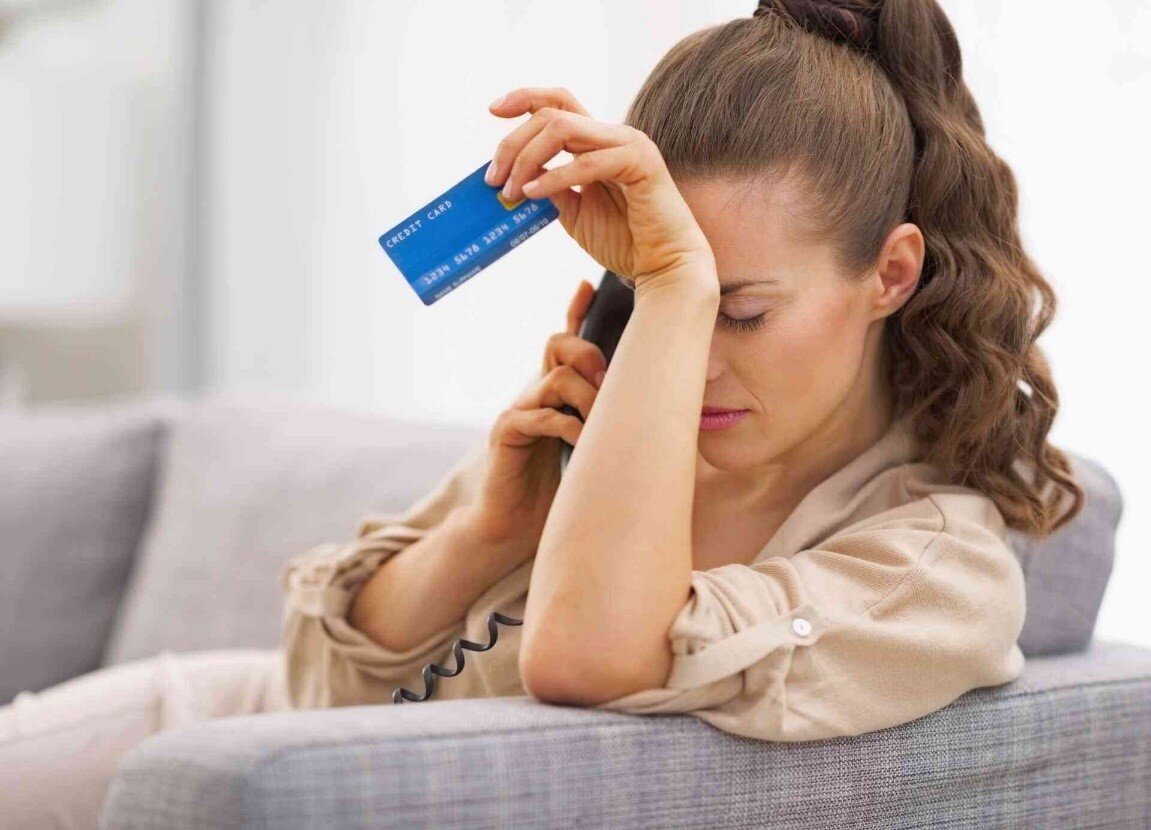 Женщина с банковской картой. Расстроенная девушка с телефоном. Девушка с кредиткой. Грустная женщина.