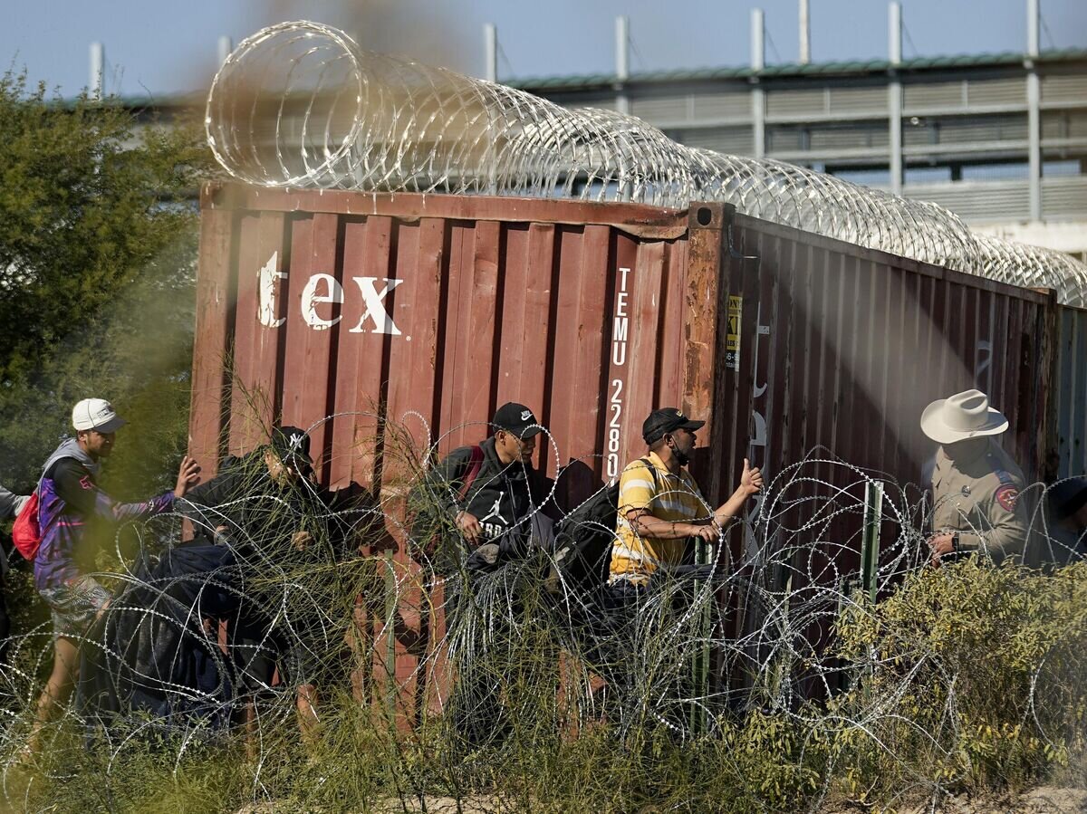    Сотрудник Департамента общественной безопасности штата Техас наблюдает за мигрантами из-за колючей проволоки на границе Техаса с Мексикой© AP Photo / Eric Gay