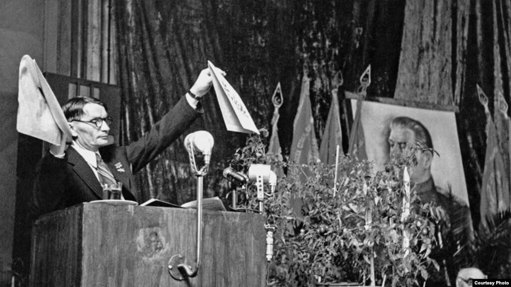 Трофим Лысенко на трибуне сессии ВАСХНИЛ, 1948, демонстрирует гербарные образцы ржи и пшеницы, утверждая, что одно из растений превратилось в другое/ © ТАСС