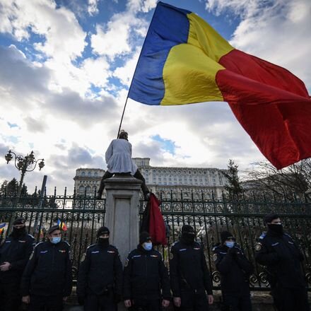 Участник протеста, организованного партией AUR, размахивает румынским флагом перед парламентом в Бухаресте.