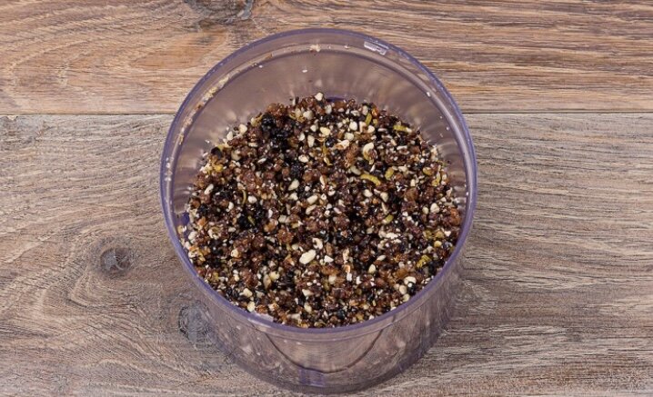 В чашу блендера выложите миндаль, сушёную смородину и изюм и измельчите их в крошку.