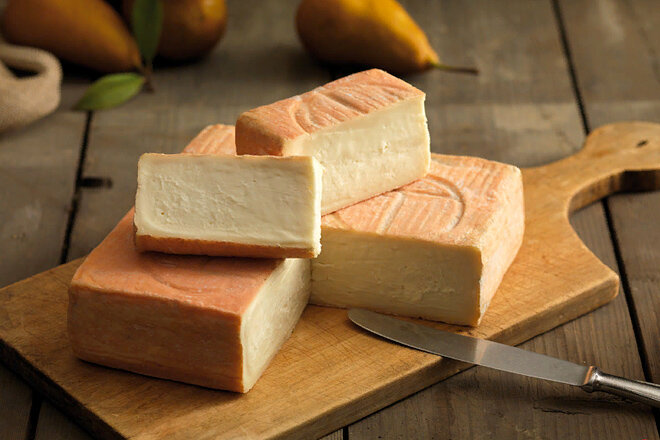 1. Талледжио

Этот итальянский сыр впервые приготовили в 10 веке. Возможно, это один из самых старых мягких сыров. В то время сыр оставляли созревать в сырых прибрежных гротах, обмывая время от времени головы сыра морской водой. По всей видимости, именно морская вода, богатая микроорганизмами, помогала талледжио приобрести славу вкусного и очень пахучего сыра. Сыр традиционно готовится осенью и зимой из-за специфичности коровьего стилонмолока в этот период. Современное производство талледжио предполагает созревание в специальных автоматах, в которых поддерживается микроклимат пещер, но то ли от недостатка свежей морской воды и свежего воздуха, или оттого, что современный сыр готовят из пастеризованного молока, талледжио 21 века не настолько пахуч, как его предки. Классический талледжио до сих пор делается небольшими партиями по старинной технологии из непастеризованного молока и с созреванием на деревянных полках в морских гротах. Раз в неделю этот сыр омывают морской губкой во избежание появления неправильной плесени. 

Талледжио имеет мягкую структуру, напоминающую масло, с тонкой корочкой оттенка древесной коры с выступающими кристаллами соли на поверхности. Вкус сыра мягкий, с фруктовыми нотками и необычным привкусом. Этот сыр можно использовать в салатах, добавлять в ризотто или поленту.