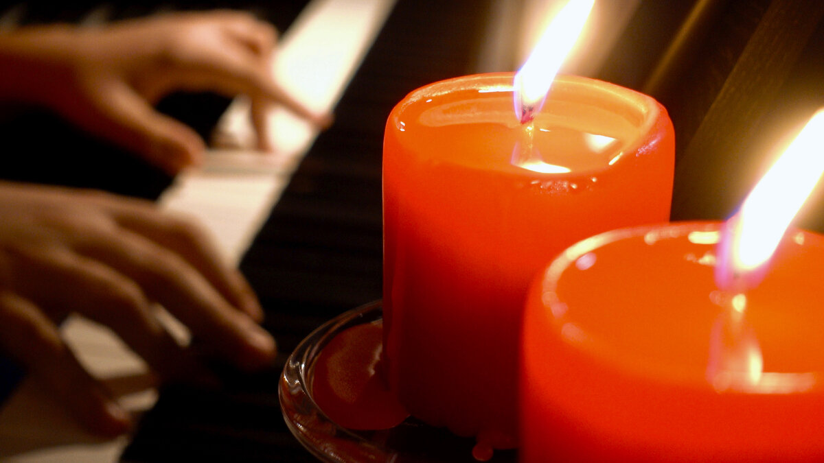 Пианист играет на фортепиано при свечах