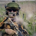    A fully equipped soldier in the camouflage uniform holding an assault rifle admin