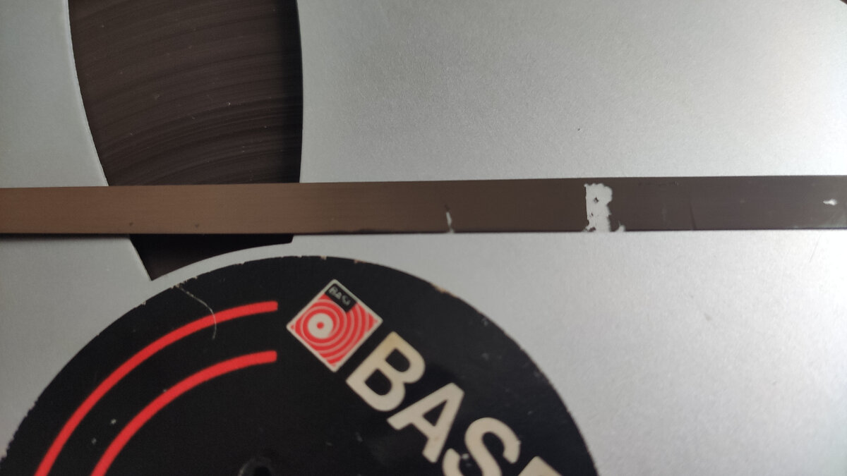 Полное отслоение магнитных частиц довольно часто встречается в начале ленты из-за скотча ракорда или зажима в пазе катушки [фото автора]