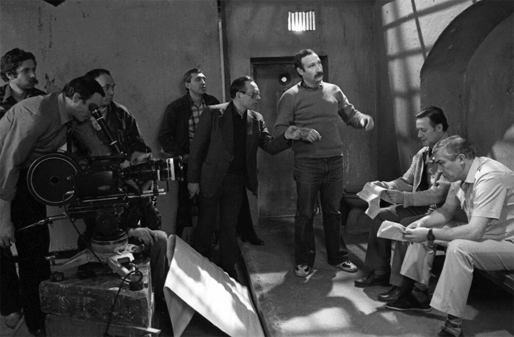    Съемки советского многосерийного художественного фильма «ТАСС уполномочен заявить... ». Автор сценария Юлиан Семенов. Режиссер Владимир Фокин. Оператор-постановщик Игорь Клебанов (третий справа). В роли полковника КГБ Славина — народный артист РСФСР Юрий Соломин (второй справа), в роли заместитель резидента ЦРУ Джона Глэбба народный артист Грузинской ССР Вахтанг Кикабидзе (справа). Центральная киностудия детских и юношеских фильмов им. М. Горького. 1983 г. Фото:  РИА Новости/ Галина Кмит