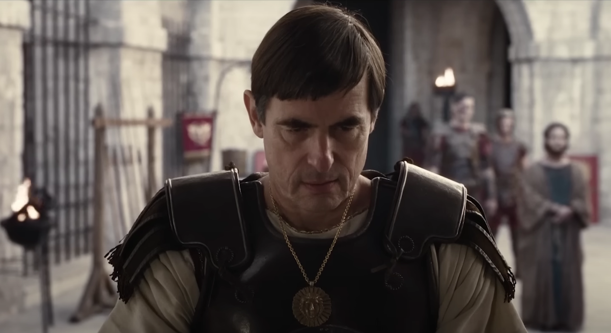 Датский актер Клас Банг в роли Понтия Пилата в фильме «Мастер и Маргарита» (2024).  Пилат носит странный кожаный доспех и медальон — видимо, с изображением Непобедимого Солнца.