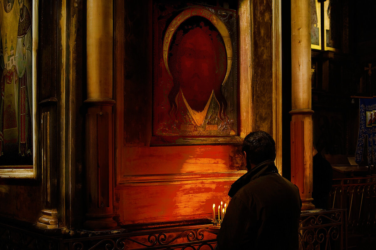 Мужчина в церкви. Мужчина молится в храме. Люди в храме. Полумрак в храме.