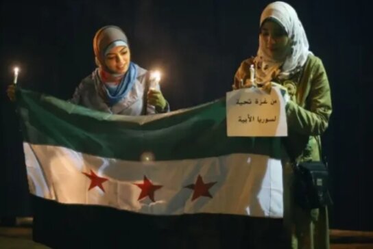 Женщины Газы держат флаг сирийских повстанцев во время акции протеста перед штаб-квартирой ООН. Изображение издания Military watch. 