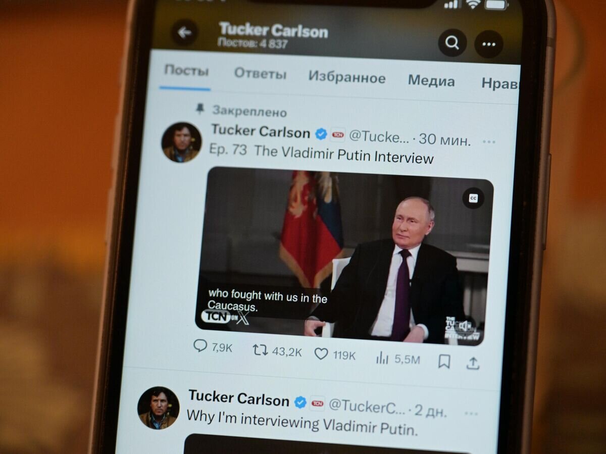    Трансляция интервью президента РФ Владимира Путина американскому журналисту Такеру Карлсону на экране телефона© РИА Новости / Александр Кряжев