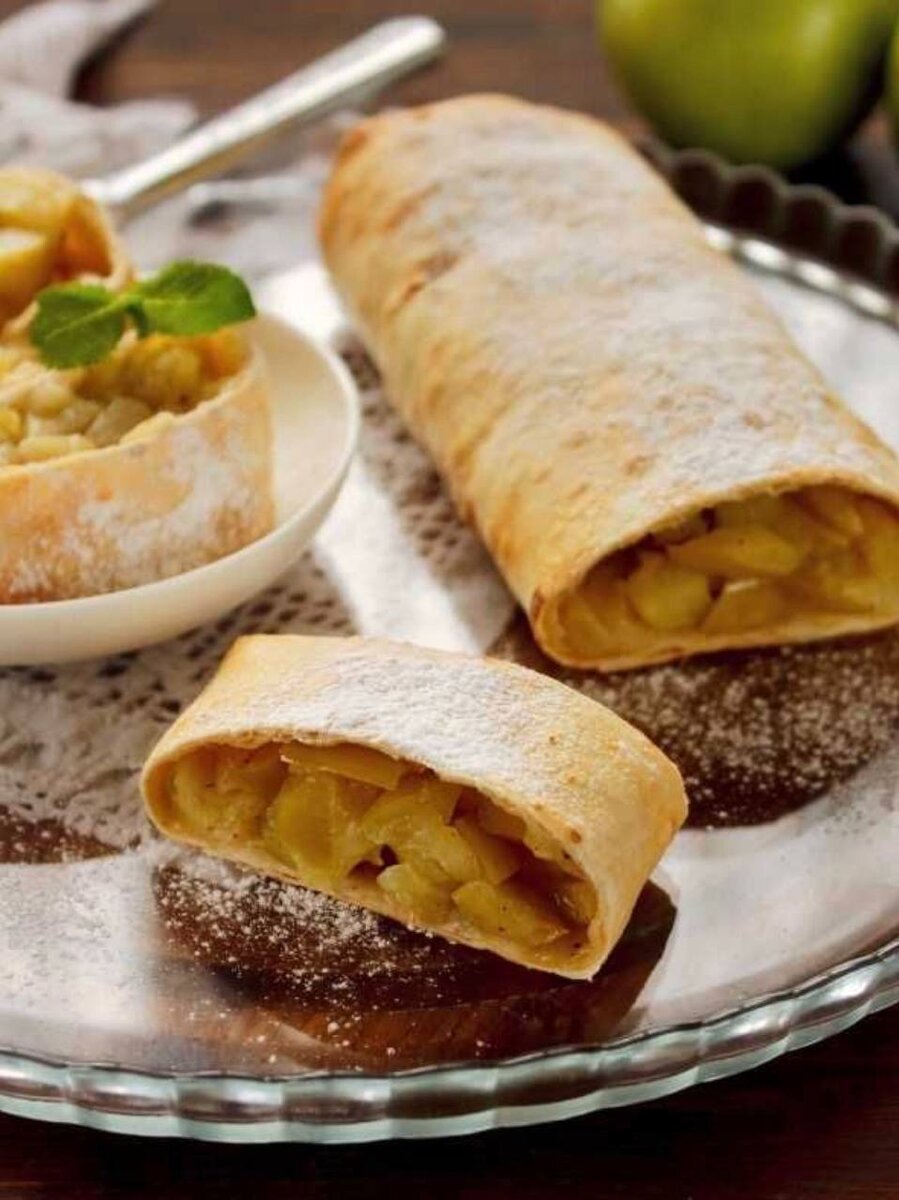 Сегодня предлагаю вам самый ленивый из всех штруделей. 

Итак, что нам нужно:
 ⁃ 1 большое сладкое  молодильное яблоко 
 ⁃ горсть крупного светлого изюма без косточек
 ⁃ горсть очищенных фисташек, порубить
 ⁃ цедра 1 апельсина
 ⁃ 1/2 ч.л корицы
 ⁃ 1 ч.л сахара
 ⁃ 50 г сливочного масла
 ⁃ мёд по вкусу и совести
 ⁃ 1 тонкий лаваш

Что делаем:
 1. Яблоко очищаем от кожуры, удаляем сердцевину и нарезаем мелкими кусочками. Цедру апельсина измельчаем - можно порубить ножом, можно измельчить в блендере, можно на терке. 

 2. В миске смешиваем нарезанное яблоко, измельченную цедру, фисташки, изюм, корицу и сахар.

 3. В сковороде разогреваем половину сливочного масла, выкладываем в неё смесь яблок и компании и готовим на среднем огне, помешивая 5 минут.

 4. На столе раскладываем лаваш и выкладываем на него обжаренные фрукты и орехи. Аккуратно сворачиваем рулетом.

 5. Разрезаем рулет на 2, 3 или 4 части и обжариваем их на оставшемся масле.

 6. Перекладываем на красивую тарелку и поливаем мёдом. Хотите сверху/рядом мороженое. 

Дальше что? Чай/кофе/танцы и разговоры!

Если в морозилке у вас есть фило тесто - смело в него крутите. 

Приятного аппетита.