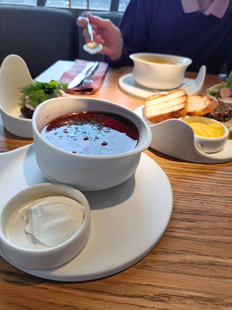 Борщ с настоящей сметаной. Подаётся с бутербродом с салом. Хлеб пекут сами.