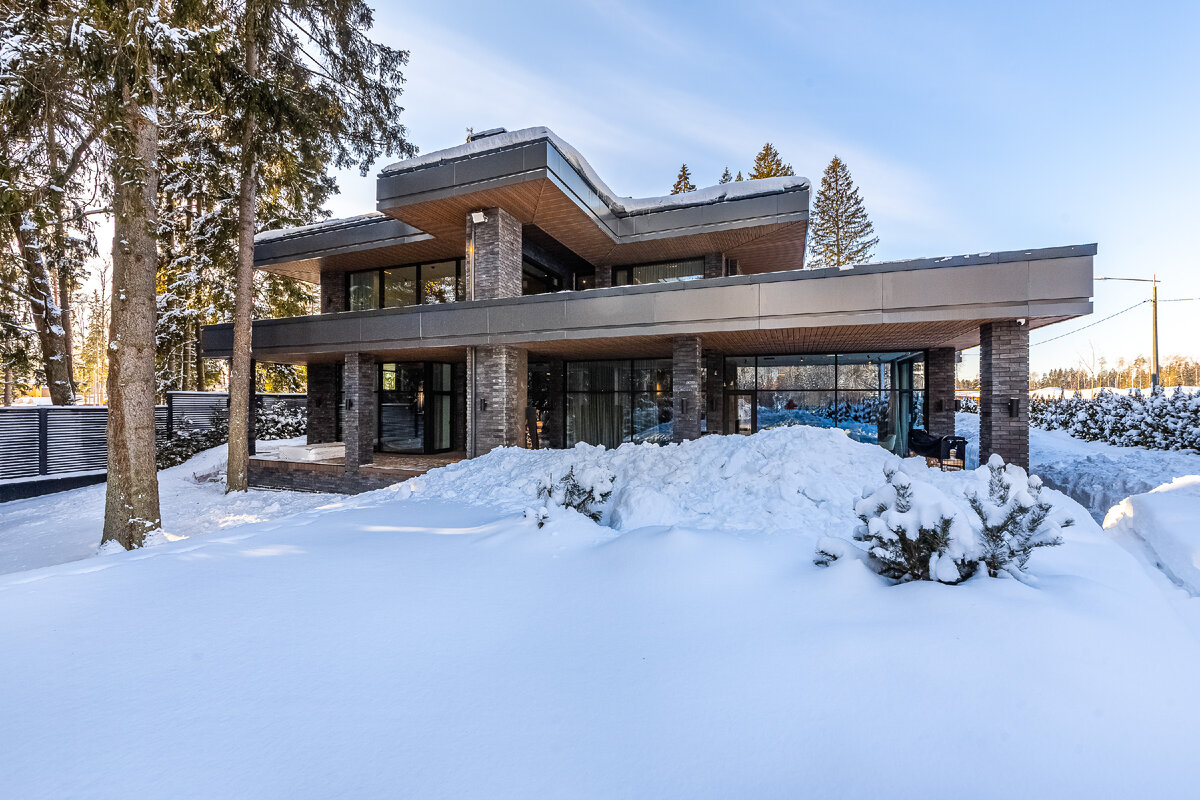 Вид на дом с участка, который находится в лесу у реки