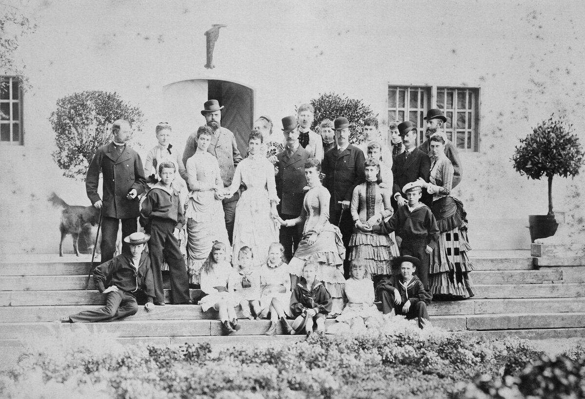 Лето 1883 года. Цесаревич Николай стоит в первом ряду слева, задумчиво глядя в даль. В верхнем ряду выделяется его отец, император Александр III в прогулочной шляпе. Король Кристиан IX стоит в верхнем ряду слева, рядом с собакой.