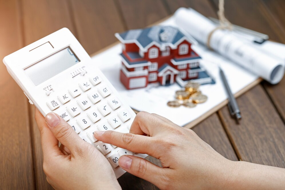 https://img.freepik.com/free-photo/a-female-hand-operating-a-calculator-in-front-of-a-villa-house-model_1387-956.jpg?w=996&t=st=1708338231~exp=1708338831~hmac=ffa934684eb3a34de9a47d328fdfcece22b36453dc6ede879208e60f1f73fbc1