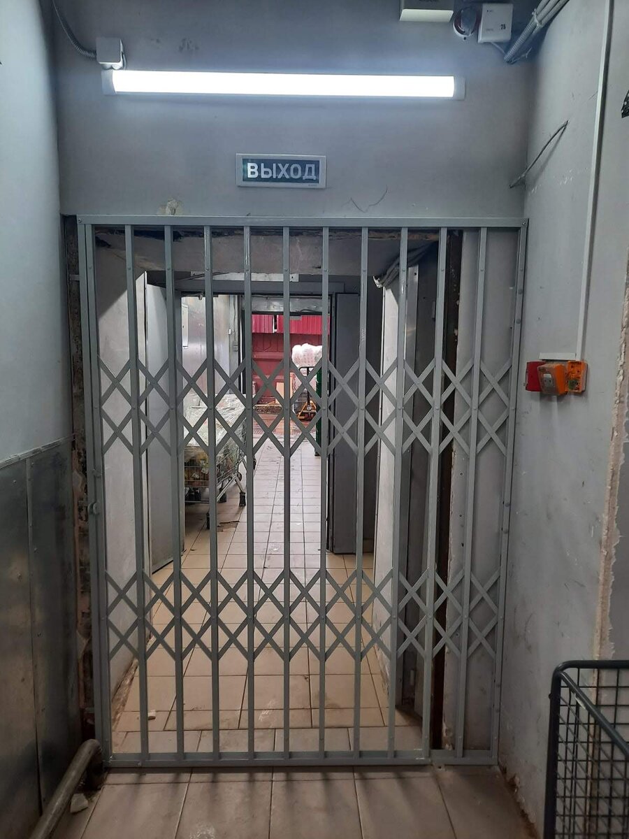 Защитная металлическая сдвижная решетка перегородка для подсобного помещения в продуктовом магазине - закрыто