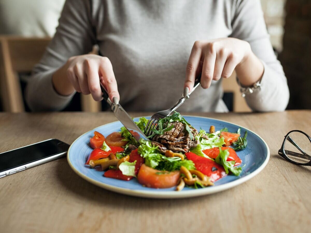    Девушка ест мясо и салат© Фото : Freepik / senivpetro