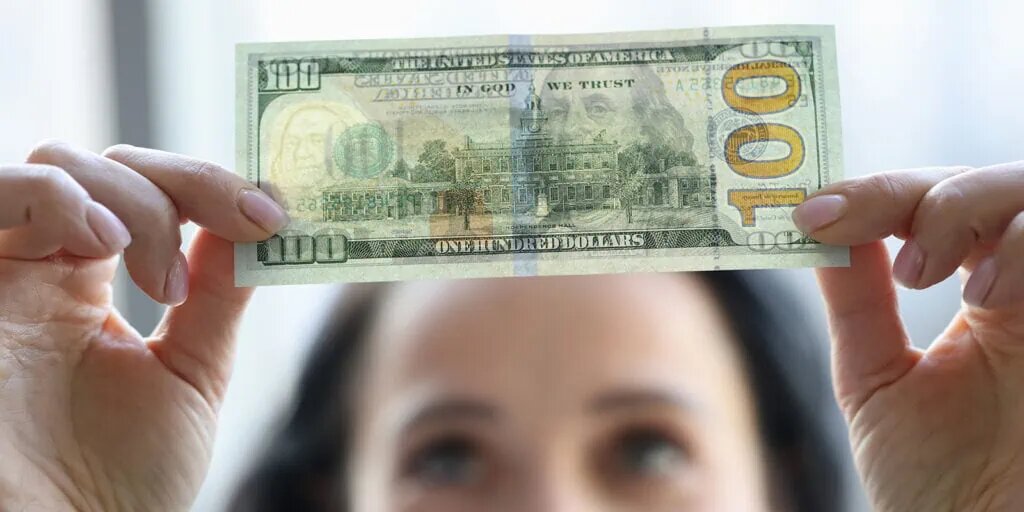    Woman holding dollar bill and looking at it with watermarks closeup. Counterfeiting money concept; Shutterstock ID 1874227390; purchase_order: 1; job: ; client: ; other: Айша Кутубаева