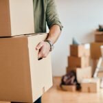    Close-up of a man with carton boxes moving into new home. admin