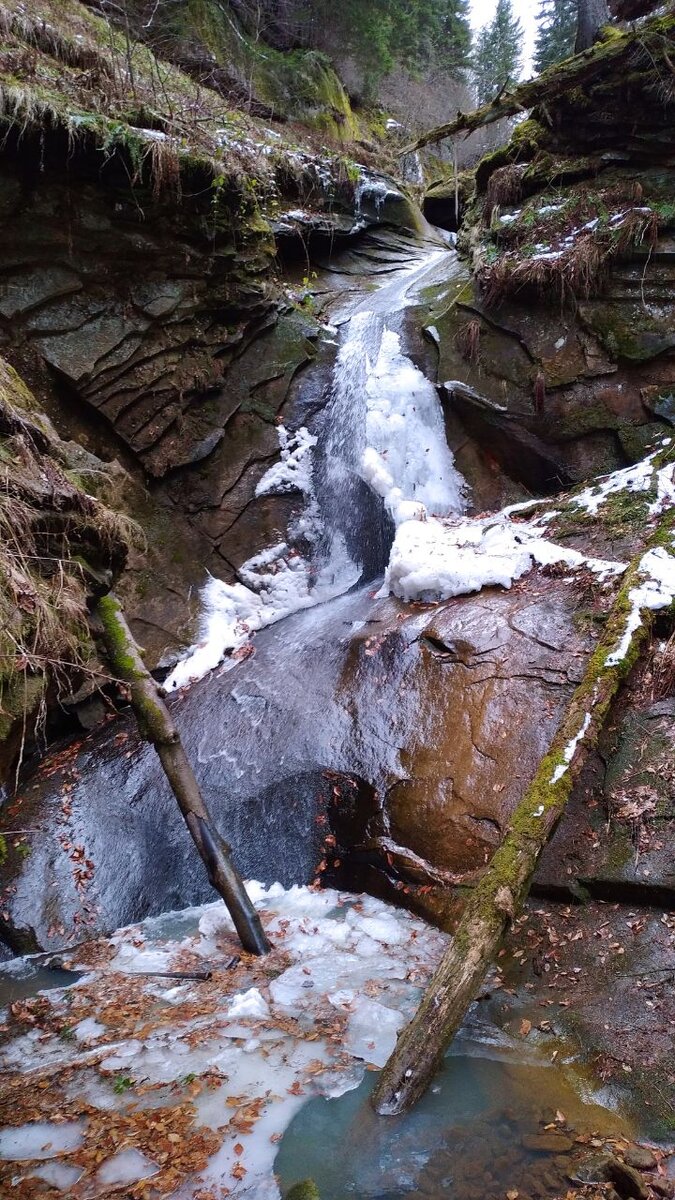 Небольшой зимний водопад протекающий по лесу реки Венгерка