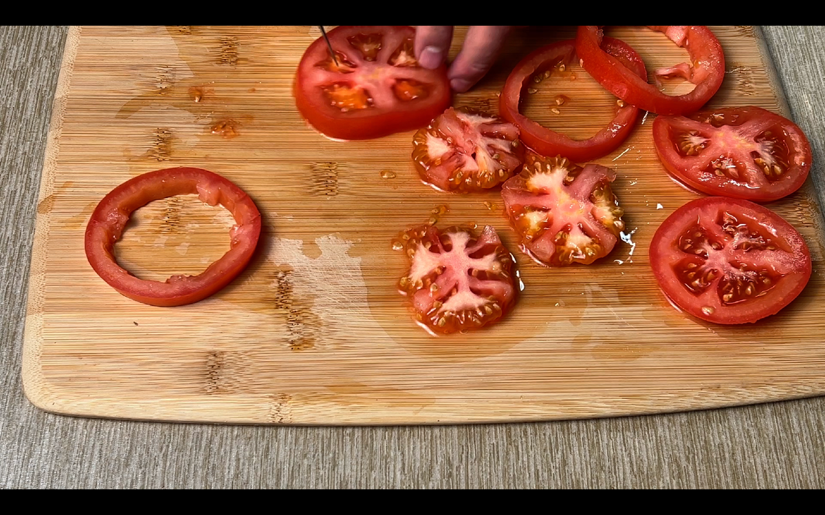 Для приготовления этого простого блюда нам нужно разбить два яйца, нарезать кольцами два средних помидора, вырезать из них середину и мелко ее нарезать, потом добавить нарзанные помидоры к яйцам(сами кольца пока уберем в сторону).