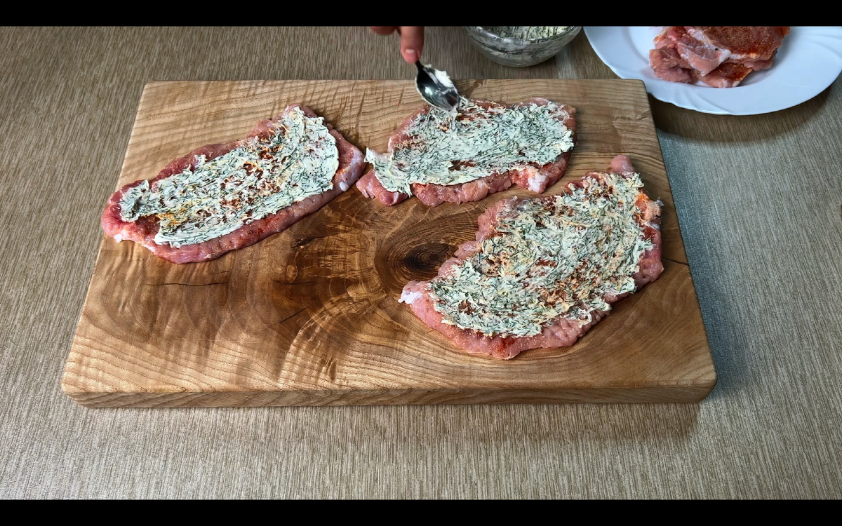 Теперь берем 100г сливочного масла, добавляем в к нему 40г мелко напезанного укропа, хорошо перемешиваем и намазываем на отбивные. Заворачиваем наши рулетики из свинины,как показано на фото.