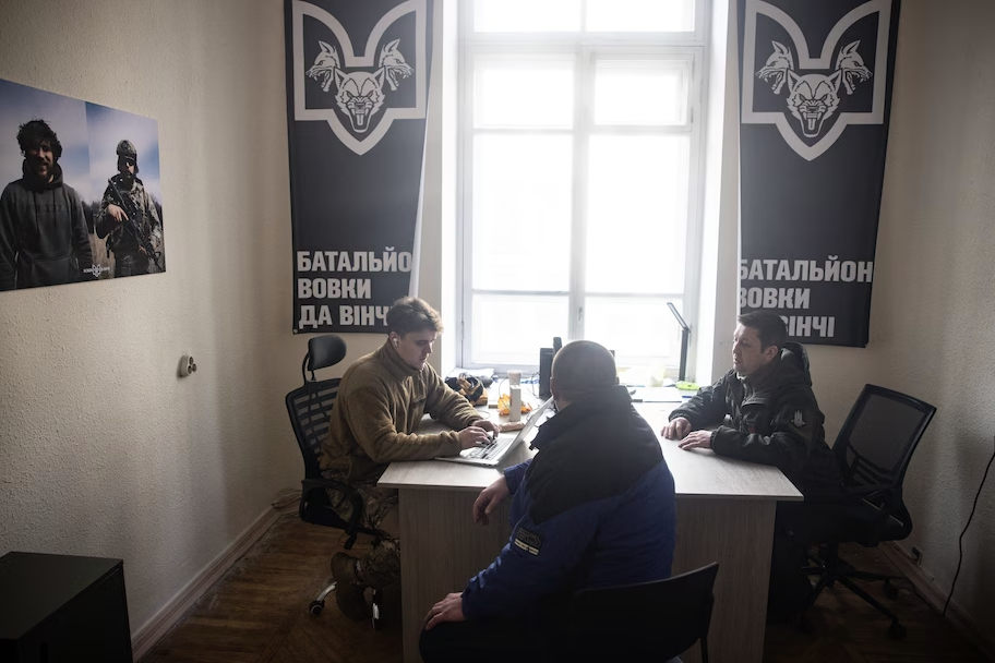 Макс, офицер по набору в батальон «Волки Да Винчи» (слева), разговаривает с 39-летним Михаилом (в центре) во время собеседования по набору в Киеве, 22 февраля © Chris McGrath/Getty Images