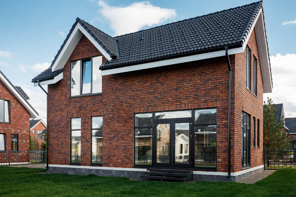 Вокруг дома сделана отмостка из брусчатки, а цоколь дома отделан декоративным  камнем.