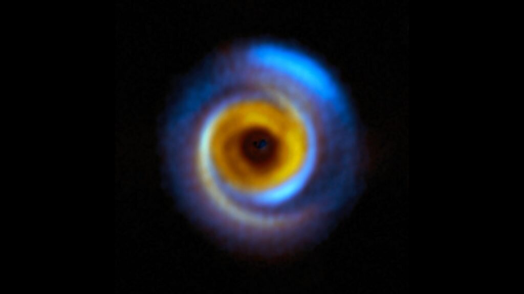    This composite image shows the MWC 758 planet-forming disc, located about 500 light-years away in the Taurus region, as seen with two different facilities. The yellow colour represents infrared observations obtained with the Spectro-Polarimetric High-contrast Exoplanet REsearch (SPHERE) instrument on ESO’s Very Large Telescope (VLT). The blue regions on the other hand correspond to observations performed with the Atacama Large Millimeter/submillimeter Array (ALMA), in which ESO is a partner. These facilities allow astronomers to map how dust is distributed around this and other stars in different but complementary ways. SPHERE captures light from the host star that has been scattered by the dust around it, whereas ALMA registers radiation directly emitted by the dust itself. These observations combined help astronomers understand how planets may form in the dusty discs surrounding young stars. Александр Шереметьев