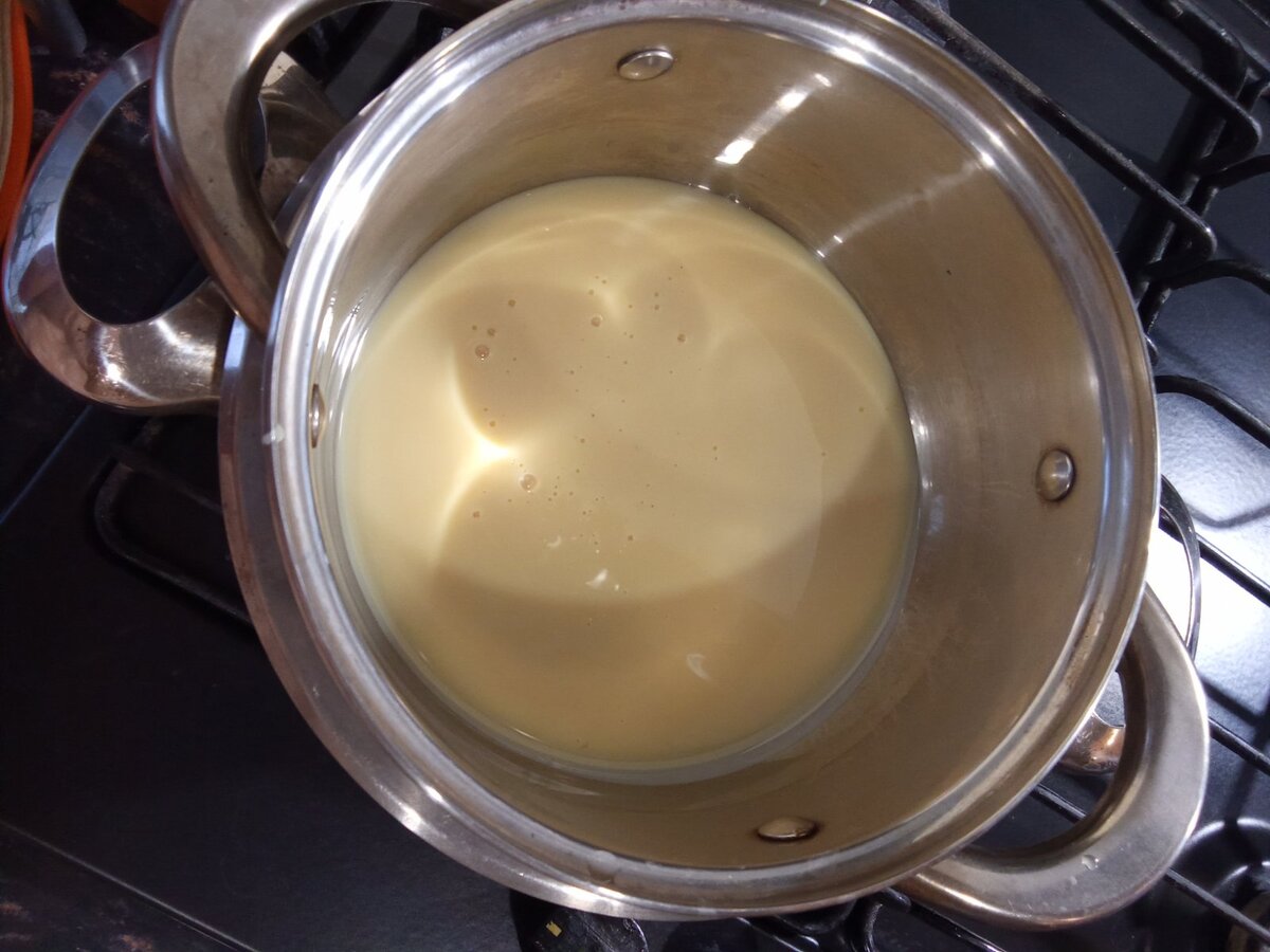 Сначала нужно подготовить сгущённое молоко. Открыть банку, перелить в кастрюлю и варить около часа на водяной бане, периодически помешивая.
