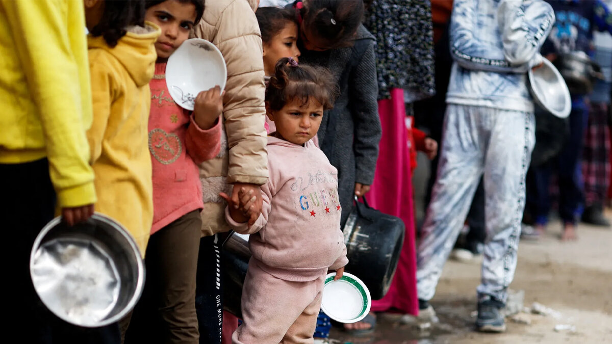 Палестинцы стоят в очереди за получением продовольственной помощи в Рафахе.