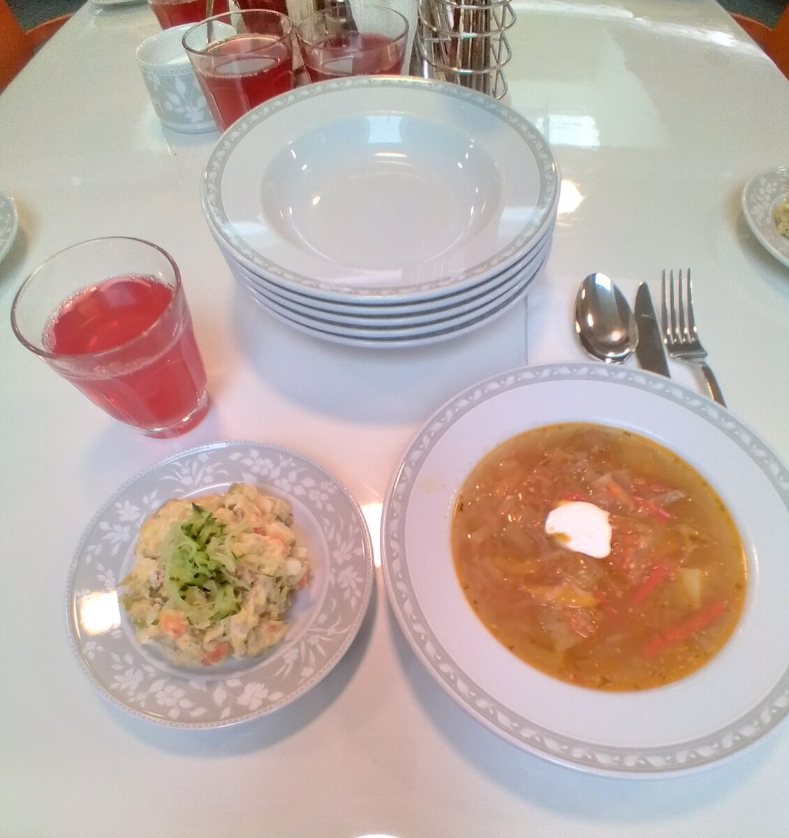 Обед, вид сверху: столичный салат, щи из свежей капусты, клюквенный морс.