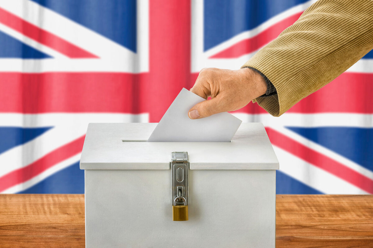    47062863 - man putting a ballot into a voting box - united kingdom editor