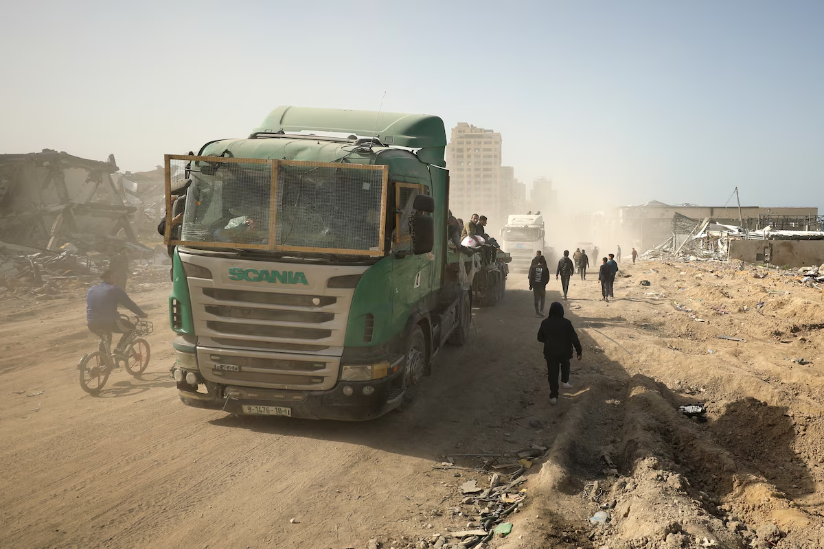 Палестинцы перевозят мешки с мукой на кузове грузовика во время доставки гуманитарной помощи в город Газа 6 марта.  