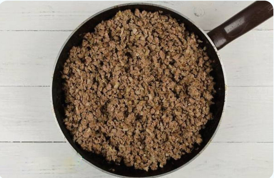 Возьмите одну луковицу нашинкуйте кубиками, добавьте на сковороду растительного масла и обжарьте его. Далее добавляем фарш и продолжаем обжаривать постоянно перемешивая, солим и добавляем специи по вкусу. Заливаем томаты в собственном соку в фарш и тушим ещё несколько минут.