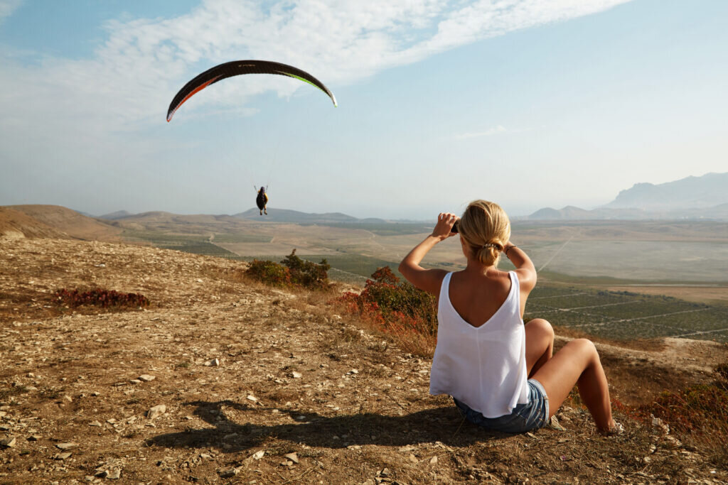 young woman hiker taking photo with smart phone at mountain peak.