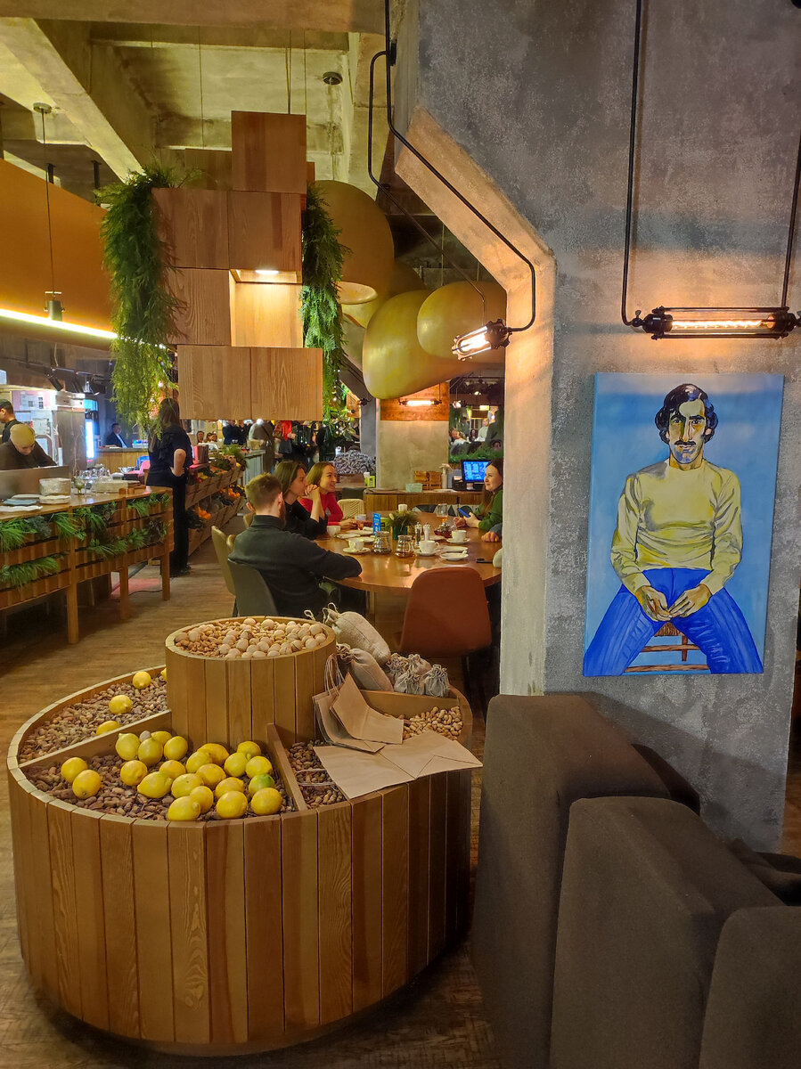Медные плафоны на потолке, импровизированный базар с яблоками, лимонами и орехами, которыми гости могут угоститься совершенно бесплатно, настоящая грузинская печь, много зелени и три портрета, ставшие