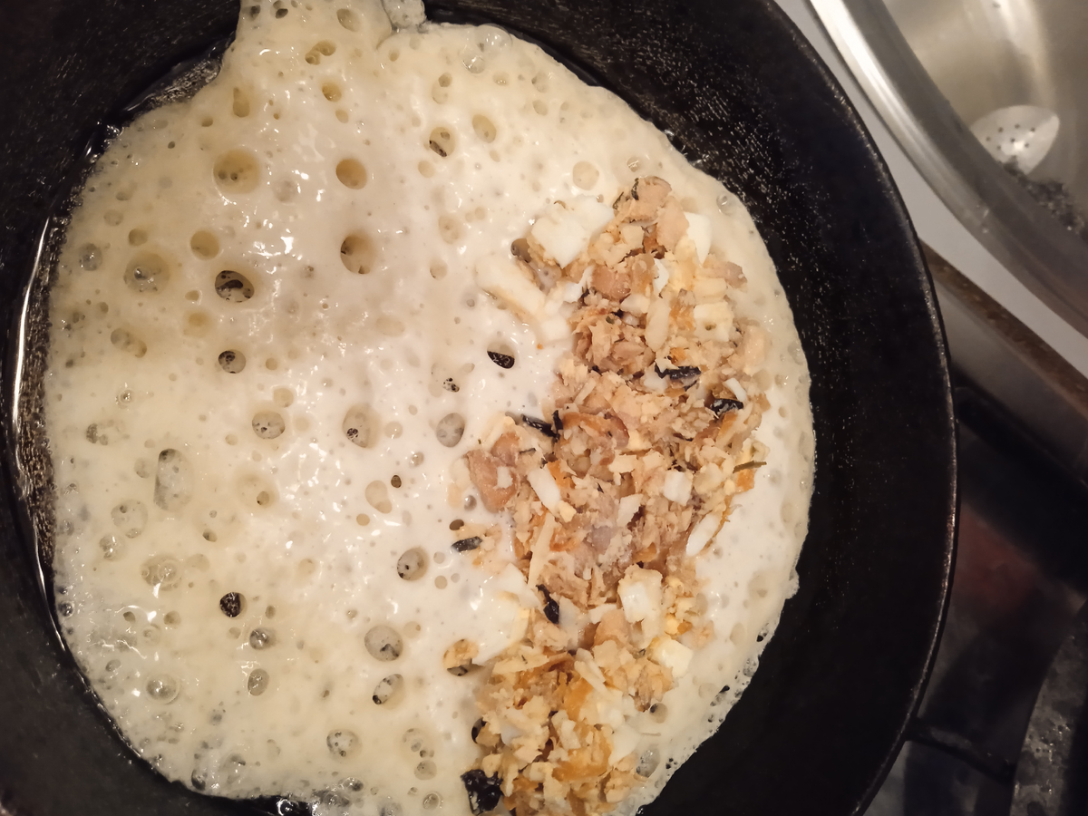 А тесто какое получилось восхитительное! Всё блины в дырочках. На одну половинку блина выкладываем начинку и накрываем второй. Отварная горбуша пережаренная с овощами была в морозилке. Я в неё ещё яйца варёные добавила