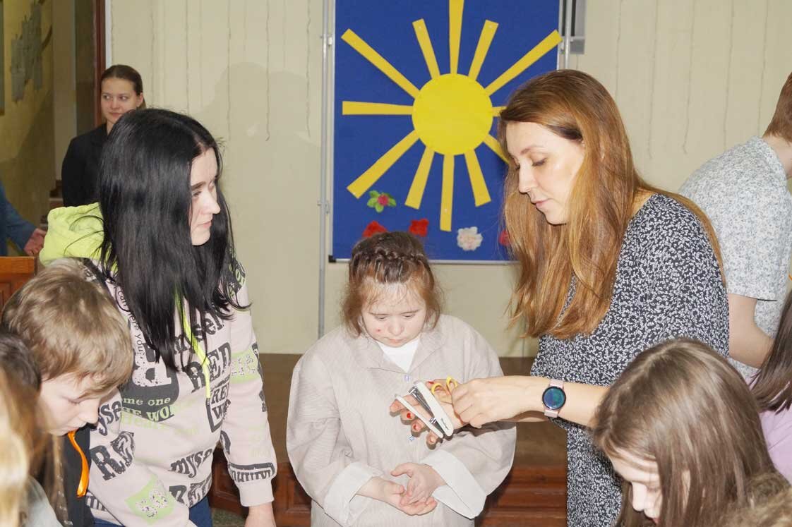 Работница ДКЖ Ксения Ефимова помогает детям делать солнечные браслеты