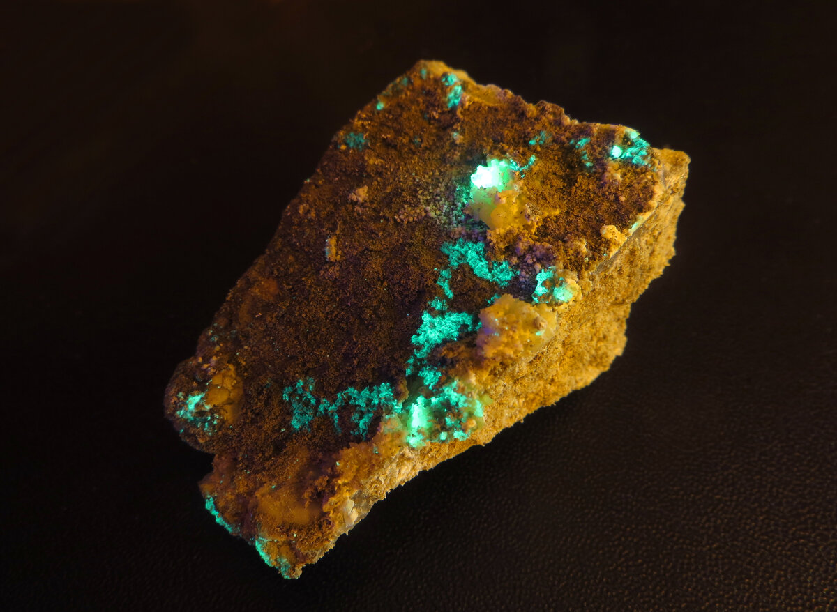 Бирюзовая люминесценция страссманнита на вмещающей породе. Быкогорское урановое месторождение.