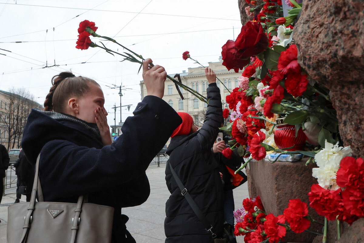 Люди возлагают цветы к стихийному мемориалу в память о жертвах теракта в подмосковном «Крокус Сити Холле» в Санкт-Петербурге, 23 марта 2024 года    📷