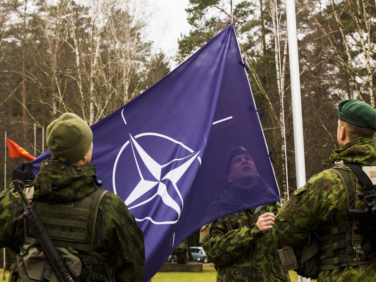    Военнослужащие поднимают флаг НАТО© Sgt. Kirstin Merrimarahajara