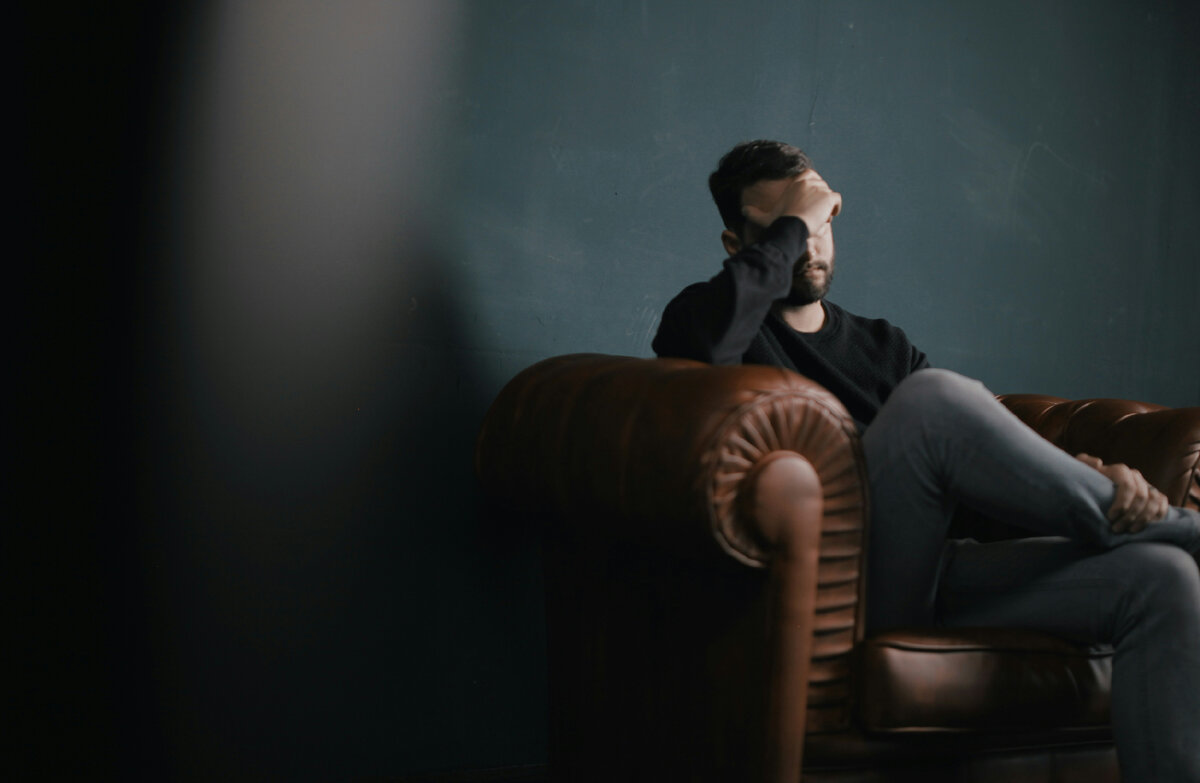 https://unsplash.com/photos/a-man-holds-his-head-while-sitting-on-a-sofa-BuNWp1bL0nc?utm_content=creditShareLink&utm_medium=referral&utm_source=unsplash