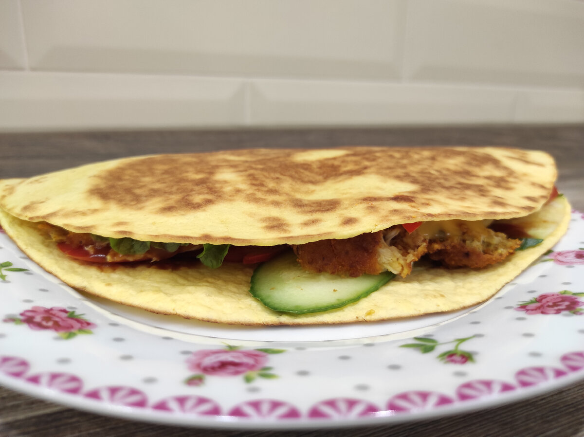 Тортилья, листья салата, огурец, помидор, болгарский перец, плавленый сыр, лук репчатый, курица, соус Цезарь