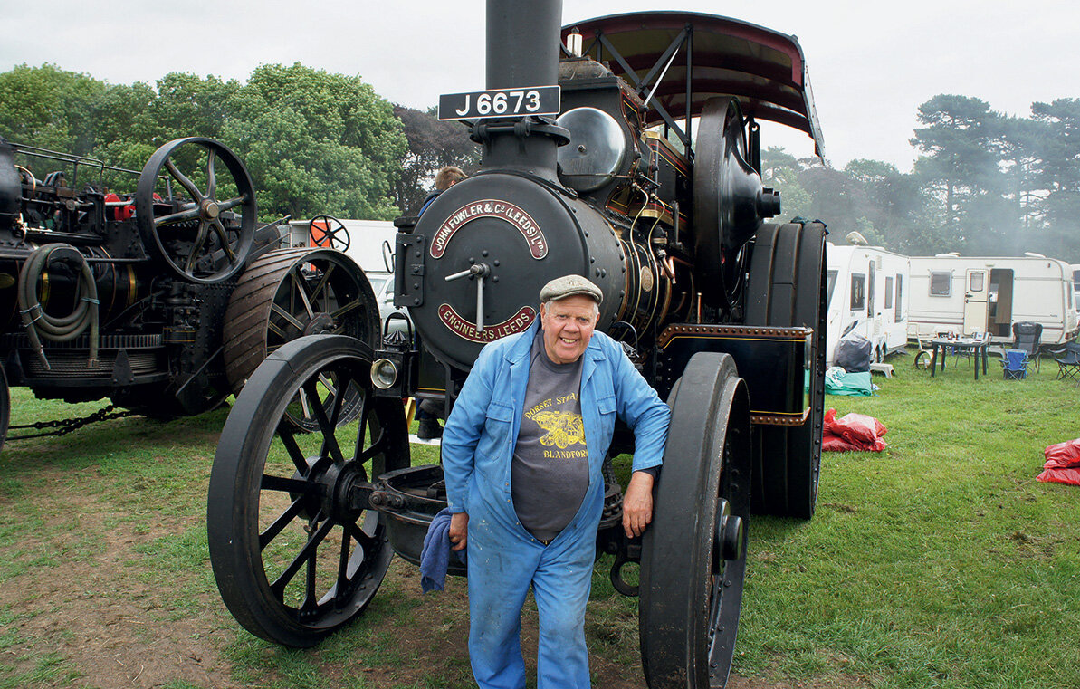 Доброжелательный и общительный реставратор рядом со своим трактором Fowler.