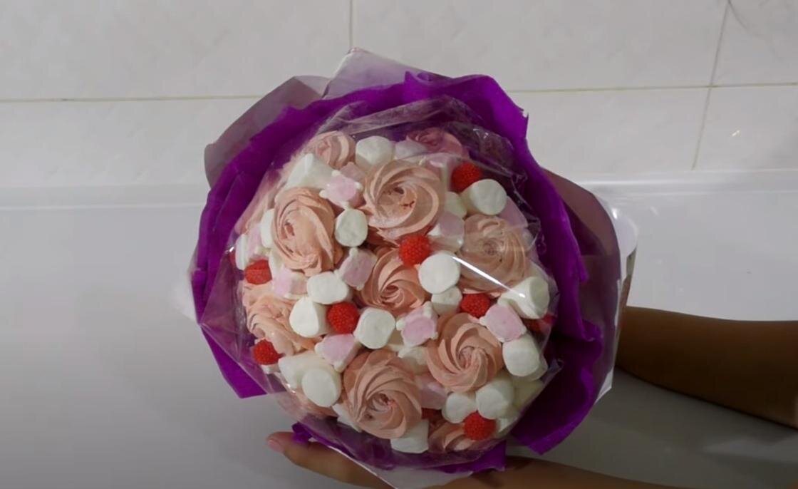    В руках держат букет из зефира и маршмеллоу. Он завернут в слюду и два слоя из гофрированной и упаковочной бумаги:YouTube/Olya Tortik Домашний Кондитер