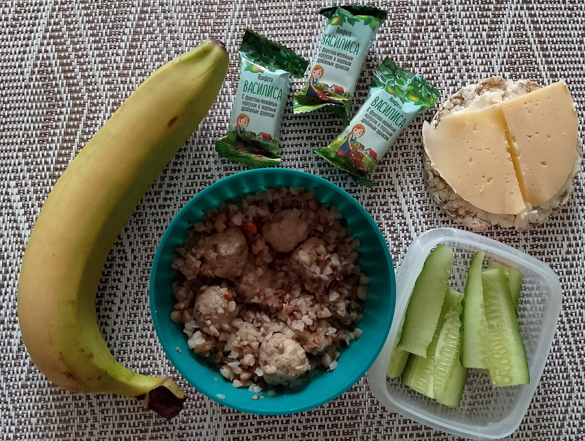 Съестные припасы на рабочий день: гречка с тефтельками и огурчиком на обед, хлебец с маслом и сыром на второй завтрак, банан на послеобеденный перекус и конфетки к чаю. Фото автора